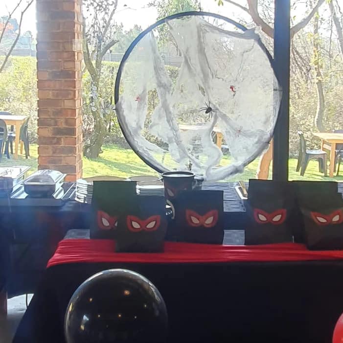 A Spiderman-themed table setting at the Barn on Boundary Party Venue in Johannesburg, Northriding featuring decorations with spider webs and masks.