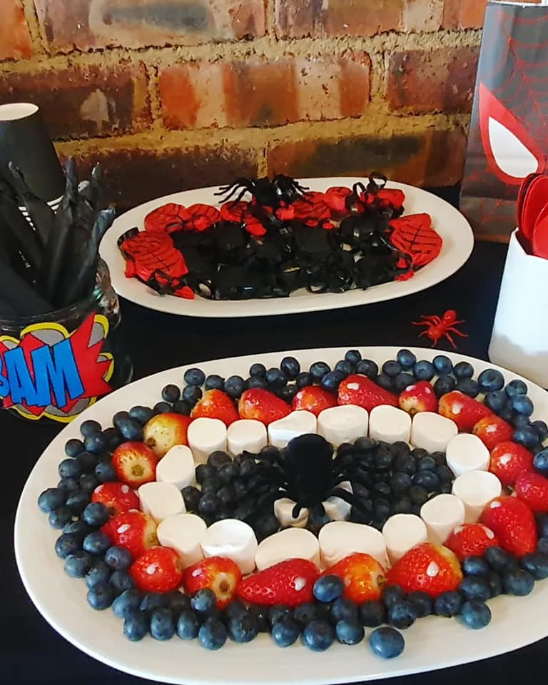 A colorful display of snacks at The Barn on Boundary Party Venue featuring a fruit platter and Spider-Man themed decorations.