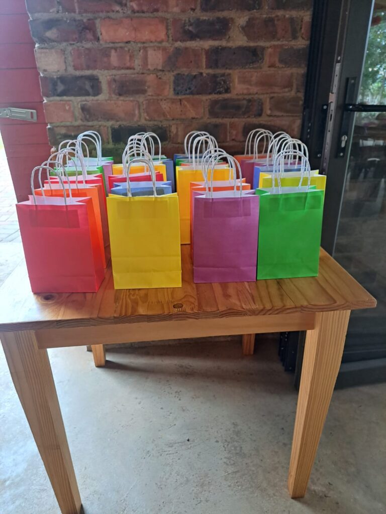 Colorful gift bags arranged on a wooden table at The Barn on Boundary Party Venue in Johannesburg, Northriding.