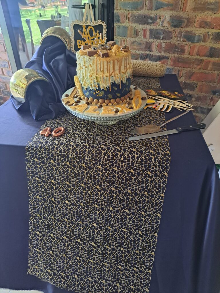 A 40th birthday cake adorned with a golden topper, surrounded by party decorations at the Barn on Boundary Party Venue in Johannesburg, Northriding.