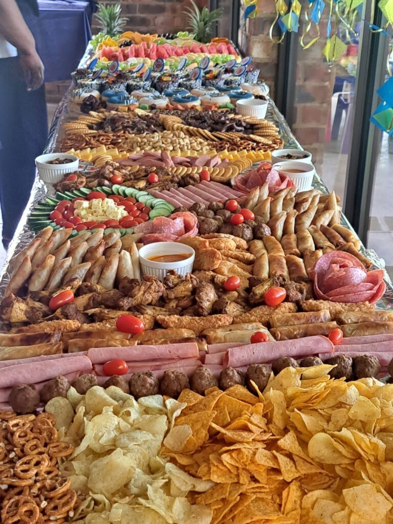 A variety of snacks and appetizers arranged on a long table covered with aluminum foil at the Barn on Boundary Party Venue in Johannesburg, Northriding.