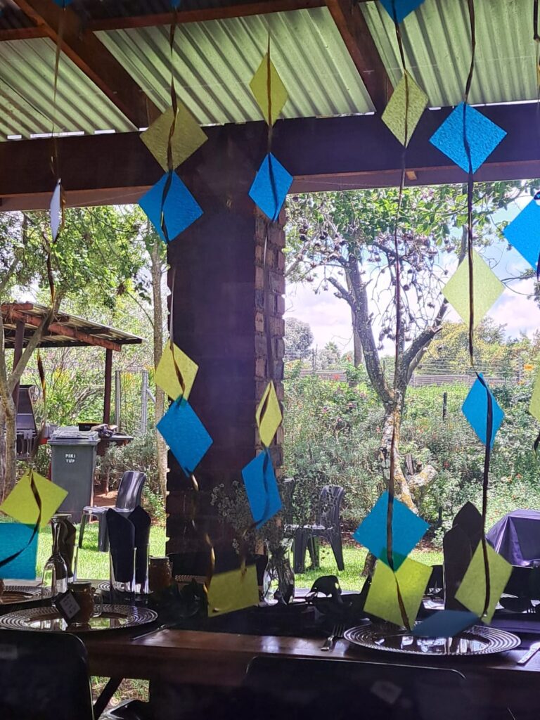 Colorful diamond-shaped decorations hanging from the ceiling of the Barn on Boundary Party Venue, with a view of the lush garden venue outside.