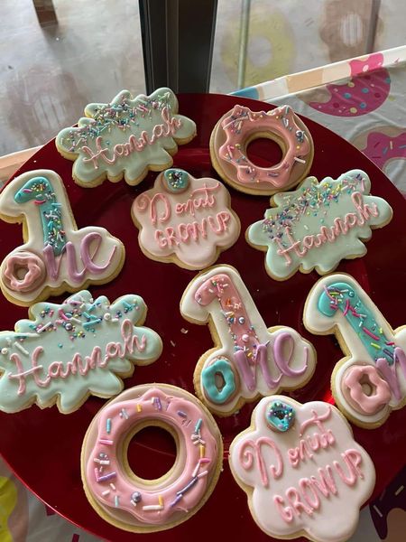 Custom decorated cookies for a first birthday celebration, including number one and donut shapes, displayed on a red plate at The Barn on Boundary Party Venue.