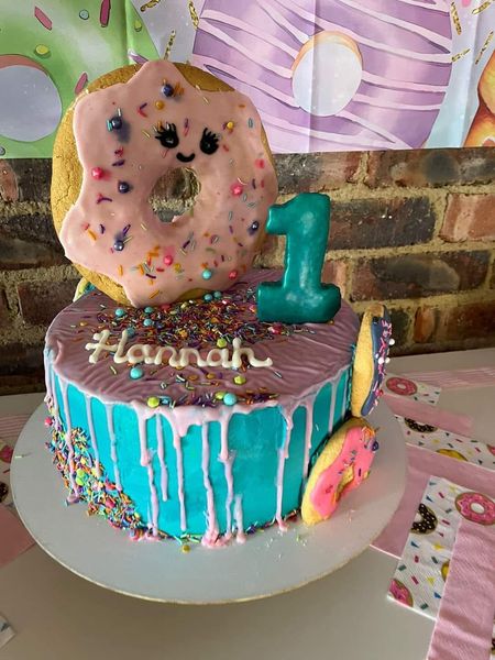 A colorful birthday cake with a number 1 topper and a donut decoration, celebrating Hannahβs first birthday at The Barn on Boundary Party Venue.